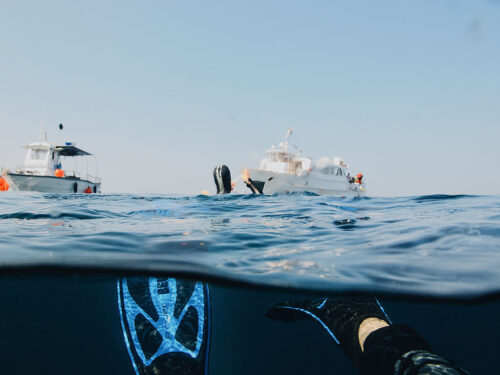 A scuba diver taking a photo of another diver and two boats