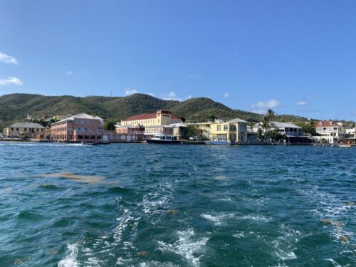 Coastline of large pastel buildings in front of hills