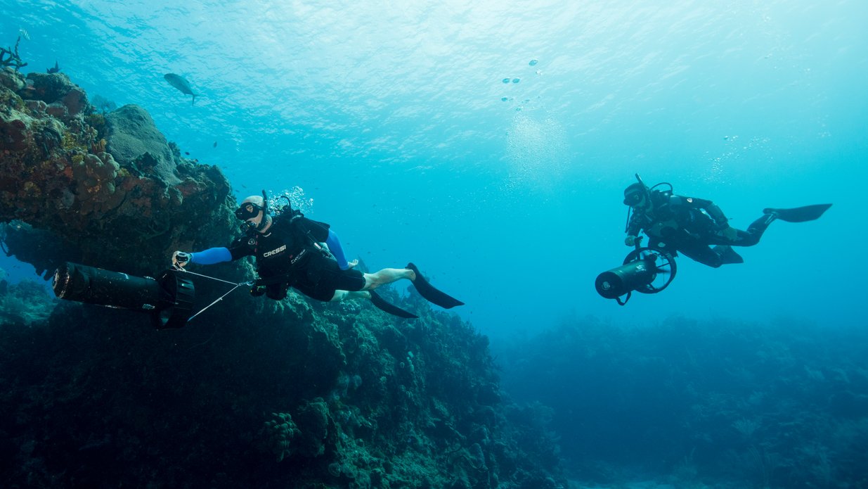 Two divers with large cameras under water