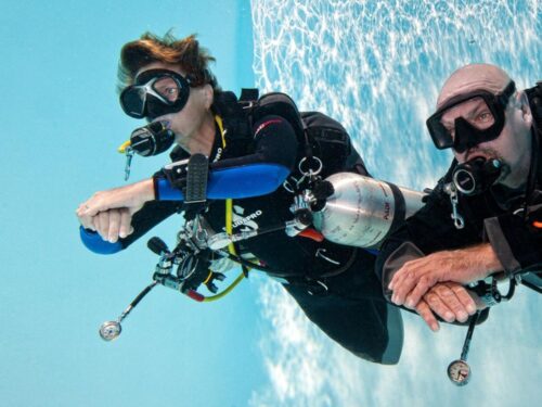 Two divers in equipment practicing in a pool